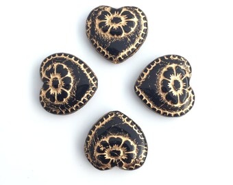 May include: Four black heart-shaped beads with gold floral designs.