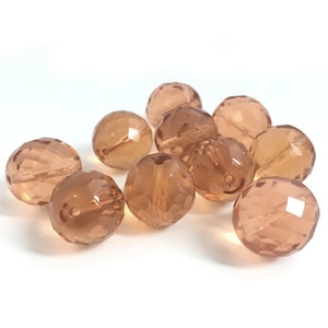May include: A group of 10 faceted glass beads in a light brown colour. The beads are round and have a smooth, polished finish.