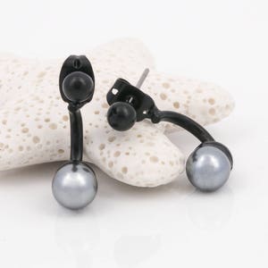 May include: A pair of black stud earrings with a curved design and a pearl on each end.