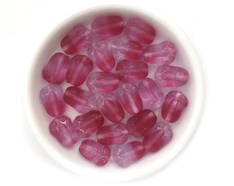 May include: A bowl of pink and purple glass beads. The beads are oval shaped and have a frosted finish.