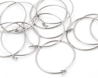 May include: A collection of silver-colored, round earring hoops with a wire closure. The hoops are scattered on a white surface, showcasing their simple, minimalist design. These earring components are ideal for jewelry making.
