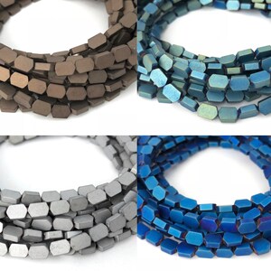 Peut inclure: Quatre brins de perles hexagonales facettées dans différentes couleurs métalliques : marron, bleu-vert, argent et bleu. Les perles sont disposées en cercle, les extrémités de chaque brin se chevauchant.