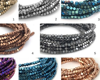 Peut inclure: Huit brins de perles facettées métalliques de différentes couleurs, dont l'or, l'argent, le bleu, le cuivre et le violet. Les perles sont disposées en rangées, chaque rangée montrant une couleur différente.