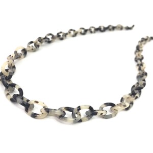 May include: A black and white patterned chain necklace made of plastic.