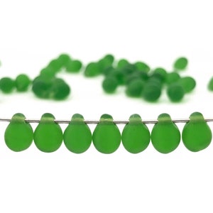 May include: A strand of eight green glass beads, each shaped like a teardrop, strung on a silver wire.