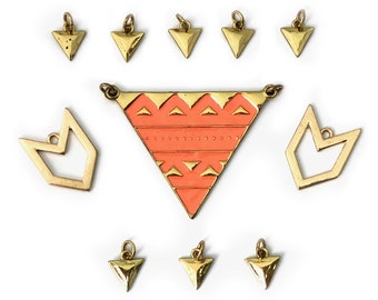 May include: A collection of gold-toned jewelry components, including triangle and geometric shapes. A large coral-colored triangle pendant with gold accents is surrounded by smaller triangles and open geometric shapes, all on a white background.