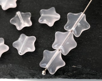May include: A strand of translucent pink star-shaped beads strung on a silver wire. The beads are made of glass or crystal and have a smooth, polished finish.