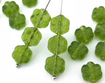 May include: A strand of green glass beads in the shape of flowers. The beads are strung on a silver wire and are separated by small silver beads. There are also loose green glass flower beads scattered around the strand.