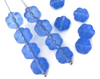 Puede incluir: Una hebra de cuentas de flores de vidrio azul claro enhebradas en un alambre plateado. Las cuentas son facetadas y tienen un acabado esmerilado.