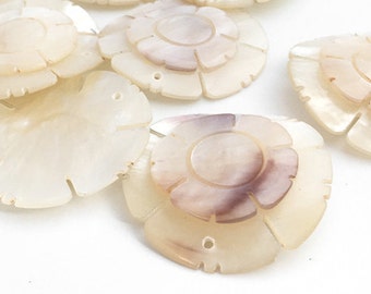 May include: A group of white and brown shell flower-shaped buttons. The buttons have a layered design and are perfect for crafting projects.