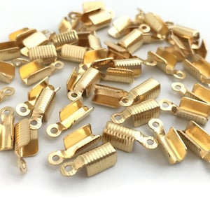 Puede incluir: Un montón de terminales de crimpado de metal dorado para la elaboración de joyas.