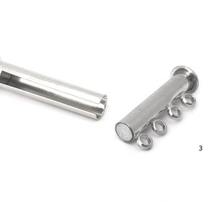May include: Silver magnetic clasp for a multi-strand necklace. The clasp has four loops for attaching strands of beads or chain. The clasp is made of two pieces, one with a magnet and the other with a hollow tube.