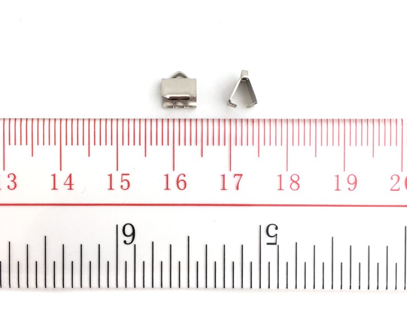 Op de afbeelding: Twee zilveren metalen sluitingen voor het maken van sieraden, gemeten met een liniaal. De sluitingen zijn ongeveer 1,2 cm lang.