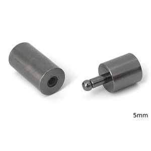 May include: Two black metal end caps for a cord or cable. The end caps are cylindrical with a small ball on one end. The end caps are 5mm in diameter.