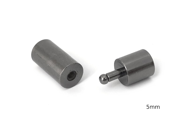 May include: Two black metal end caps for a cord or cable. The end caps are cylindrical with a small ball on one end. The end caps are 5mm in diameter.