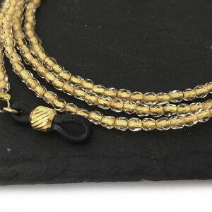 May include: A gold and clear glass beaded eyeglass chain with black rubber ends.