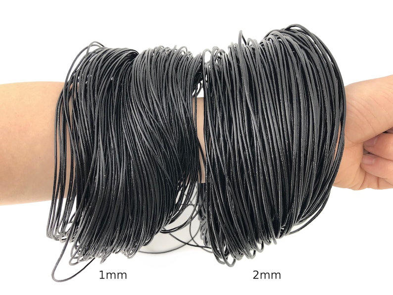 Puede incluir: Dos haces de cord&oacute;n negro, uno etiquetado 1 mm y el otro 2 mm. Los cordones est&aacute;n bien enrollados y parecen estar hechos de un material flexible. La imagen est&aacute; sobre un fondo blanco.