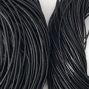 Puede incluir: Primer plano de dos haces de cord&oacute;n de cuero negro. Los cordones est&aacute;n enrollados firmemente, creando una superficie densa y texturizada. El color negro es consistente, con sutiles variaciones de brillo. Los cordones parecen nuevos y sin usar.