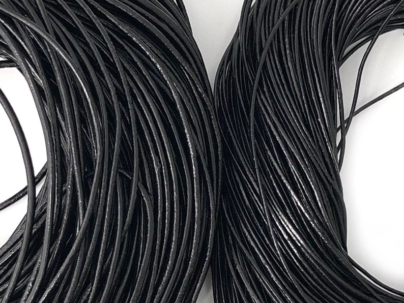 Puede incluir: Primer plano de dos haces de cord&oacute;n de cuero negro. Los cordones est&aacute;n enrollados firmemente, creando una superficie densa y texturizada. El color negro es consistente, con sutiles variaciones de brillo. Los cordones parecen nuevos y sin usar.