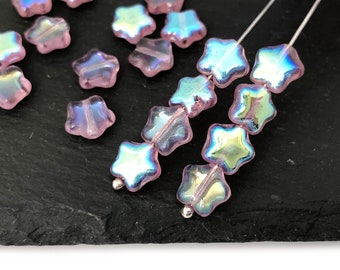 May include: Pink iridescent star-shaped glass beads strung on silver wire. The beads have a light pink colour with a rainbow iridescent sheen.