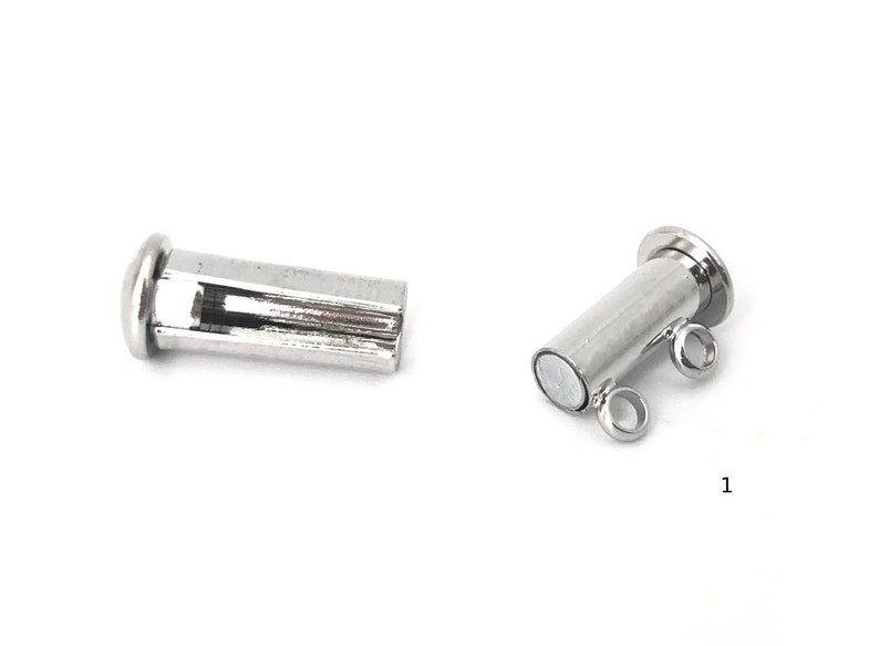 May include: Two silver magnetic clasps for jewelry making. One clasp is a simple cylinder with a flat top. The other clasp has two loops on the side and a flat top.