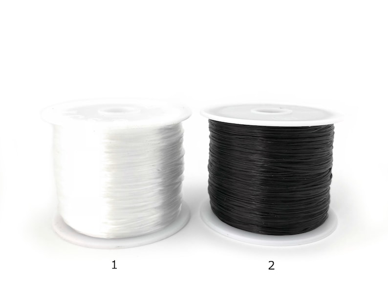 May include: Two spools of elastic cord, one white and one black, are displayed against a white background. The spools are on white plastic bases. The white spool is labeled "1" and the black spool is labeled "2".