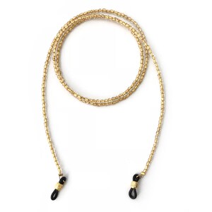 May include: A gold beaded eyeglass chain with black silicone ends. The chain is made of small, round beads and is approximately 28 inches long.