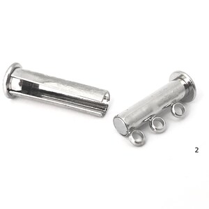 May include: Two silver magnetic clasps for jewelry making. Each clasp has a cylindrical shape with a magnetic end and three loops for attaching to a chain or cord.