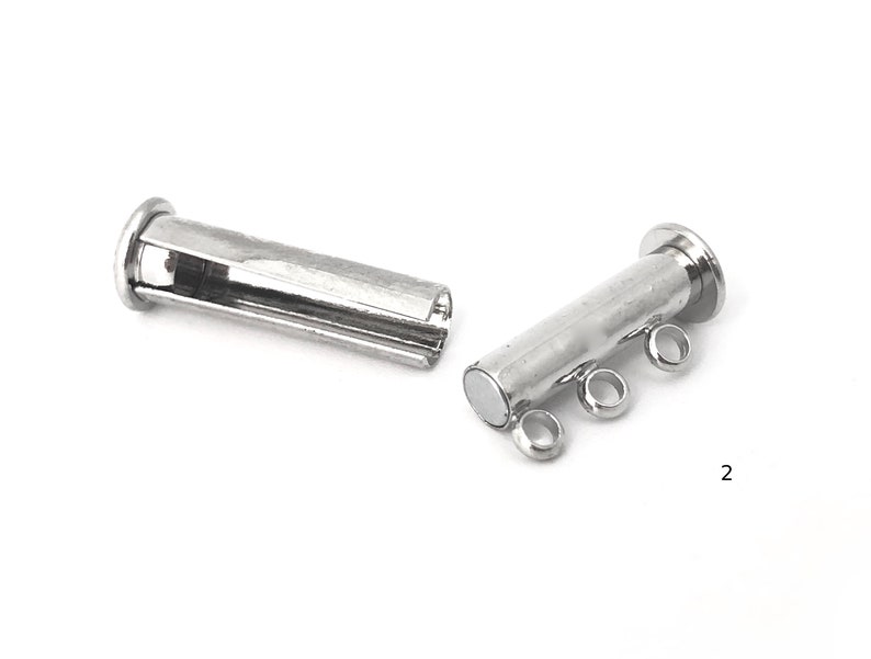 May include: Two silver magnetic clasps for jewelry making. Each clasp has a cylindrical shape with a magnetic end and three loops for attaching to a chain or cord.
