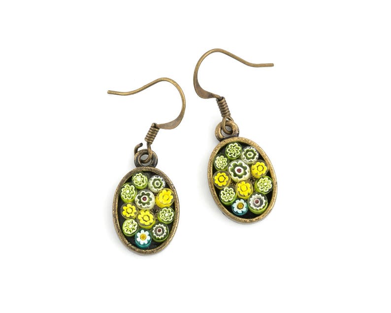 Op de afbeelding: Een paar gouden oorbellen met ovale hangers met een cluster van kleurrijke glazen bloemen. De bloemen zijn geel, groen, wit en blauw.