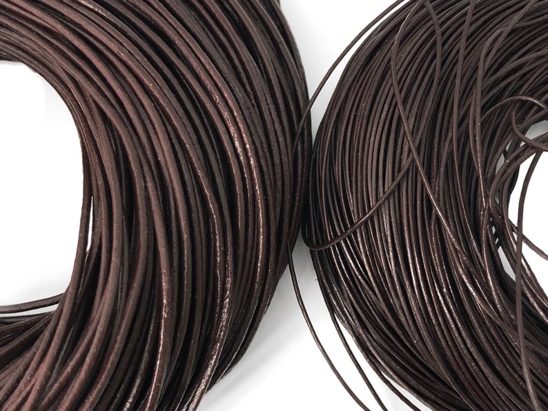 Puede incluir: Primer plano de dos bobinas de cord&oacute;n de cuero marr&oacute;n oscuro. El cord&oacute;n est&aacute; enrollado firmemente, revelando una textura suave y ligeramente brillante. El color es un tono rico y terroso, adecuado para proyectos de joyer&iacute;a o artesan&iacute;a.