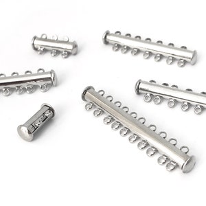 May include: Five silver-toned metal magnetic clasps for jewelry making. The clasps have different lengths and numbers of loops.