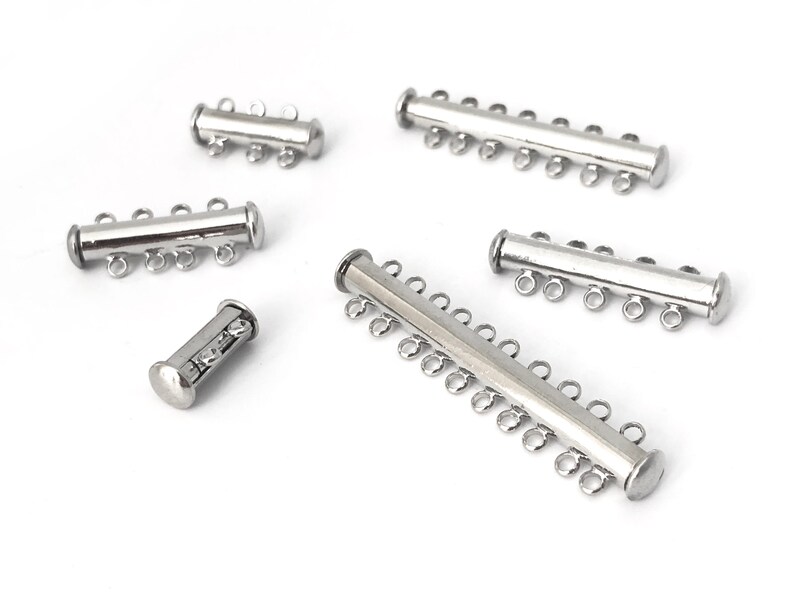May include: Five silver-toned metal magnetic clasps for jewelry making. The clasps have different lengths and numbers of loops.