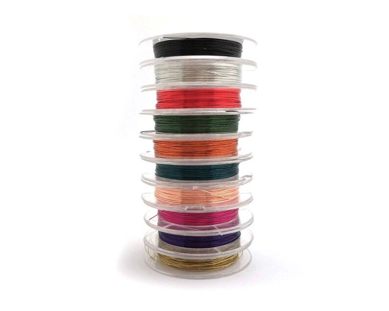 May include: A stack of spools of colorful thread, including black, white, red, green, orange, pink, purple, and gold. The spools are arranged in a tower, with the black spool at the top and the gold spool at the bottom.