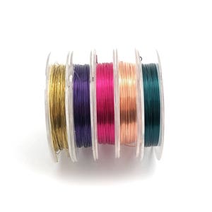 May include: Five spools of colorful wire for jewelry making. The spools are arranged in a row, with the colors from left to right: gold, purple, pink, copper, and green.