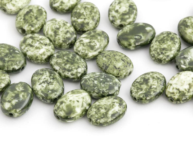 May include: A collection of oval-shaped beads with a mottled green and white pattern. The beads are smooth and glossy, with a hole drilled through each for stringing. These beads are suitable for jewelry making and crafting.
