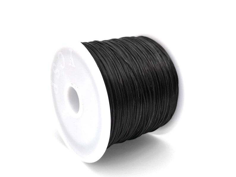 May include: A spool of black cord, tightly wound and ready for use. The cord is a solid black color and appears to be made of a durable material. The spool has a white plastic base with a central hole.