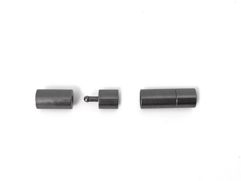 May include: A set of three black metal magnetic clasps for jewelry making. The clasps are cylindrical and have a smooth finish.