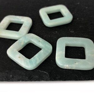 Peut inclure: Quatre perles carr&eacute;es de couleur bleu clair avec un trou carr&eacute; au centre. Les perles sont faites d'un mat&eacute;riau translucide avec une finition l&eacute;g&egrave;rement scintillante.