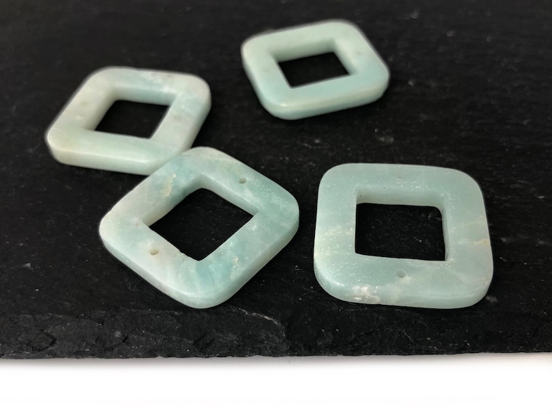 Peut inclure: Quatre perles carr&eacute;es de couleur bleu clair avec un trou carr&eacute; au centre. Les perles sont faites d'un mat&eacute;riau translucide avec une finition l&eacute;g&egrave;rement scintillante.