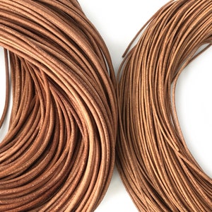 Puede incluir: Dos bobinas de cord&oacute;n de cuero marr&oacute;n se muestran sobre un fondo blanco. Los cordones est&aacute;n enrollados firmemente, mostrando su forma redonda y superficie texturizada. El cuero tiene un color marr&oacute;n natural y c&aacute;lido, lo que sugiere una est&eacute;tica r&uacute;stica o artesanal.
