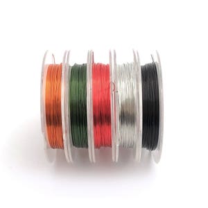 May include: Six spools of wire in different colors: orange, green, red, silver, and black. The spools are arranged in a row.