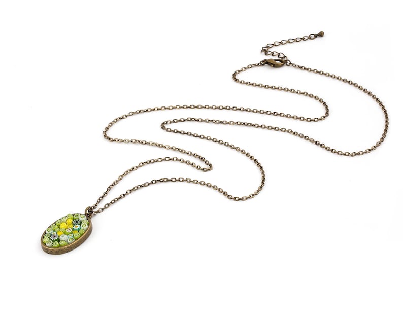 Op de afbeelding: Een gouden ketting met een ovale hanger in groen en geel. De hanger is gemaakt van kleine moza&iuml;ektegels.