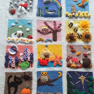 May include: A knitted wall hanging with 12 squares depicting different months of the year. Each square features a different animal, plant, or weather element. For example, the January square has a snowman, the April square has a duck, and the October square has a hedgehog.