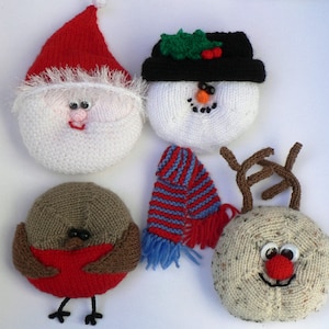 Puede incluir: Cinco adornos navideños de punto: Papá Noel, muñeco de nieve, reno, petirrojo y una bufanda. Los adornos son todos blancos con detalles rojos, marrones y negros.