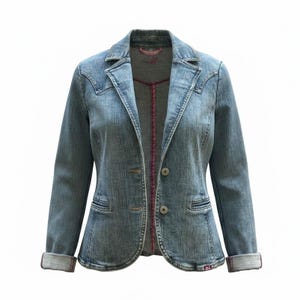 Puede incluir: Una blazer de mezclilla azul claro con cuello con muescas clásico y cierre de dos botones. La chaqueta presenta dos bolsillos delanteros y mangas enrolladas, revelando un forro rosa en contraste. El forro interior también es rosa, sobre un fondo blanco.