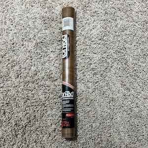 May include: A rolled-up brown on-Tract adhesive plastic roll. The label reads "on-Tract Adhesive Plastic" and "100 FT X 18 IN". The roll is brown with a wood grain pattern.