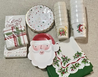 May include: A collection of Christmas-themed disposable tableware. Includes Santa Claus and round plates, cups, and napkins. The plates have a scalloped edge and a festive confetti design. Napkins feature holly and berry designs.
