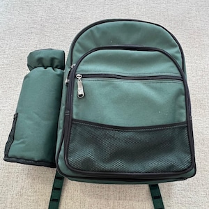 Puede incluir: Mochila verde con un portabotellas a juego. La mochila tiene un compartimento principal con cremallera, un bolsillo frontal con cremallera y un bolsillo lateral de malla. El portabotellas está adjunto. Ribete negro y correas verdes.