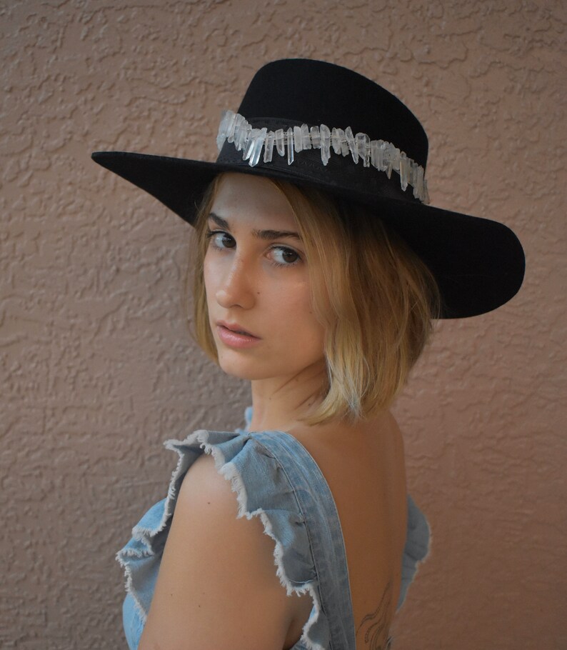 May include: A woman wearing a black felt hat with a crystal trim and a denim overall dress.